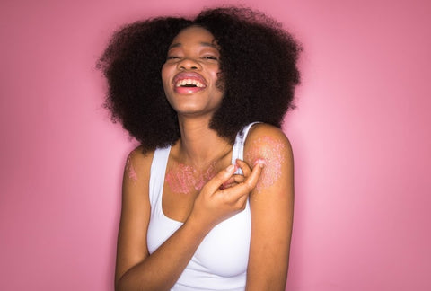 mulher negra sorrindo em frente a uma parede rosa